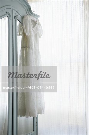 Christening gown on wardrobe at window with net curtains