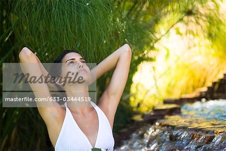 Femme relaxante de la cascade avec les mains derrière la tête