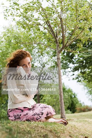 Jeune femme assis à l'extérieur, enveloppe elle-même à cardigan