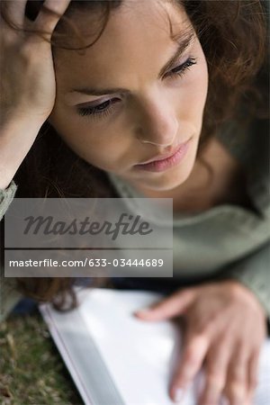 Woman holding book, looking away in distraction