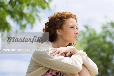 Young woman outdoors, looking away in thought