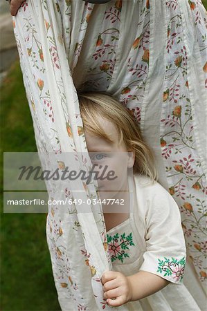 Little girl hiding behind curtains