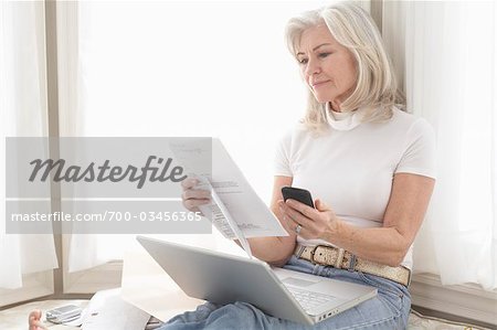 Woman with Paperwork Using Laptop and Electronic Organizer