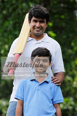 Father holding cricket bat with son