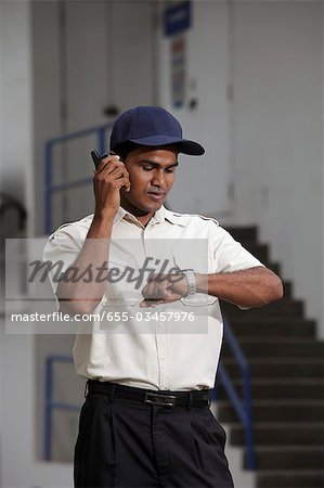 Security guard looking at watch and talking on phone