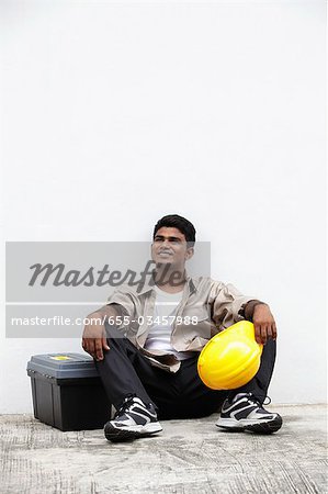 Mann sitzt auf dem Boden hält Bau