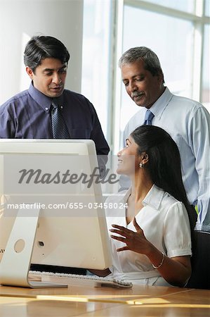 Indian business people talking to each other around a computer