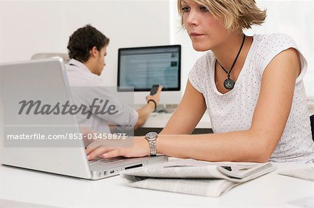 Two teenager using laptop, mobile phone and desktop computer, horizontal format