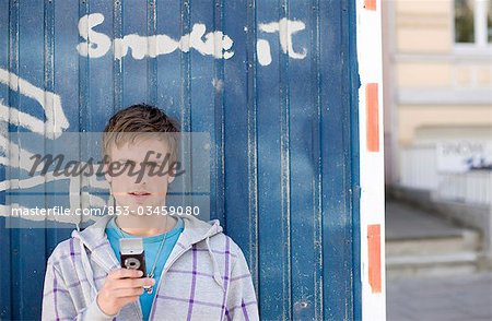 Junger Mann mit Handy vor einem Container stehen
