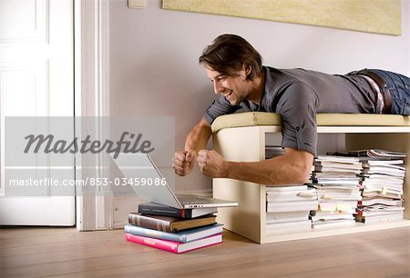 Mann, liegend auf einem Regal und mit einem Notebook, low Angle view