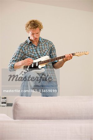 Man playing e-guitar in his apartment, low angle view