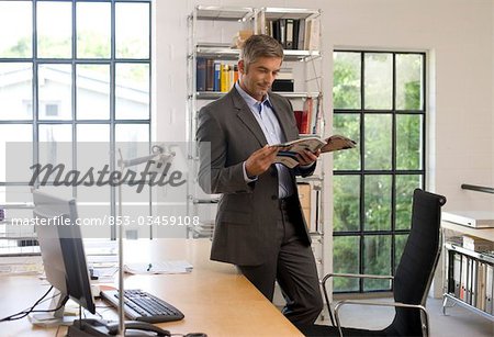 Homme lisant un magazine dans un bureau