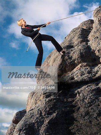 Businesswoman Climbing up Cliff