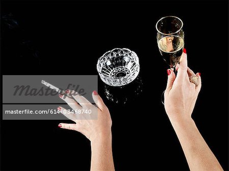 Female hand with cigarette in holder and glass of champagne