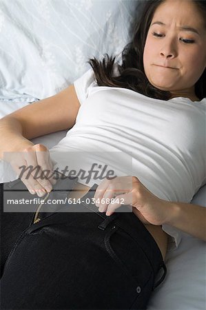 Young woman trying to do up her jeans
