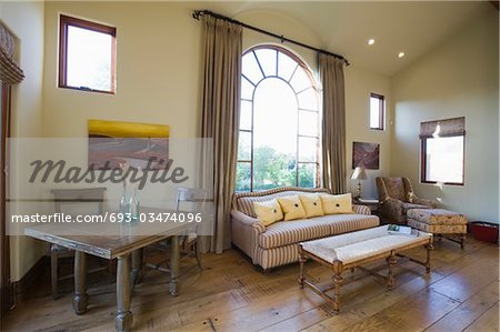 Arched window and sofa in living room with high ceiling