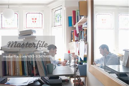mid adult man working in cluttered study