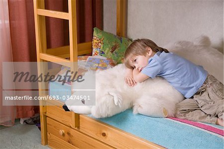 5 year old boy lies on bunk bed with polar bear soft toy