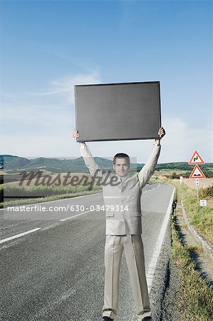 Homme debout sur le bord de la route et tenant une pancarte