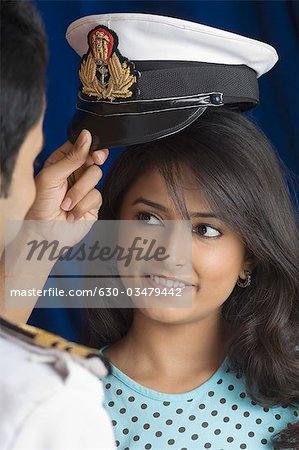 Navy officer adjusting uniform cap on a young woman's head