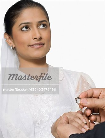 Close-up of a bridegroom's hand placing a ring on his bride's finger