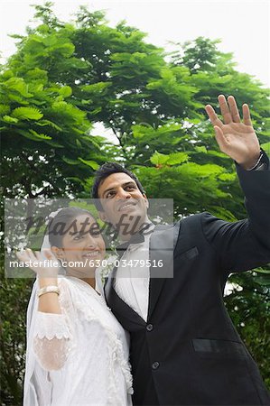 Gros plan d'un couple de jeunes mariés, agitant leurs mains et souriant