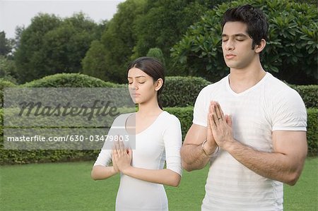 Couple practicing yoga in a park