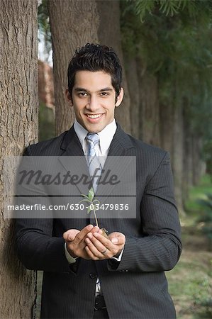Portrait of a businessman holding a plant and smiling