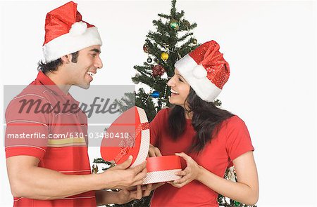 Man giving a heart shaped Christmas present to a woman