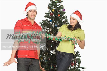 Paar vor einem Weihnachtsbaum spielen und Lächeln