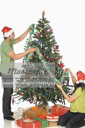 Couple decorating a Christmas tree and smiling