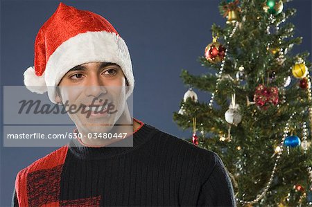 Close-up of a man smiling near a Christmas tree