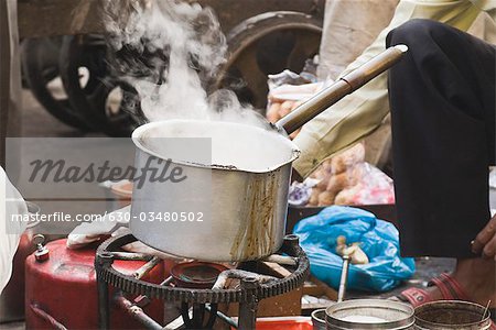 Man making tea in a market, Delhi, India