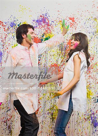 Couple dancing in front of a wall colored with Holi colors