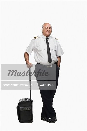 Portrait d'un pilote transportant un bagage et souriant