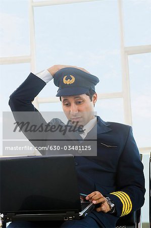 Pilot using a laptop at an airport and looking confused