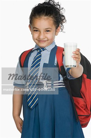 Portrait of a schoolgirl holding a glass of milk and smiling