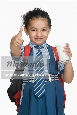 Schulmädchen Daumen hält ein Glas Milch und zeigen oben Zeichen