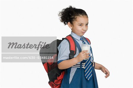 Schoolgirl holding a glass of milk and making a face