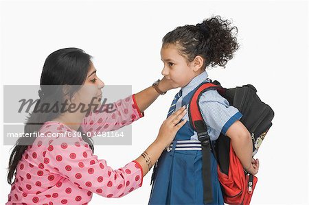 Woman preparing her daughter for school