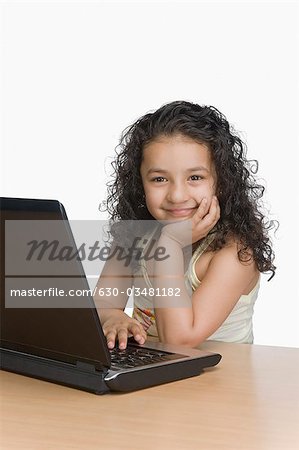 Portrait d'une jeune fille à l'aide d'un ordinateur portable et souriant