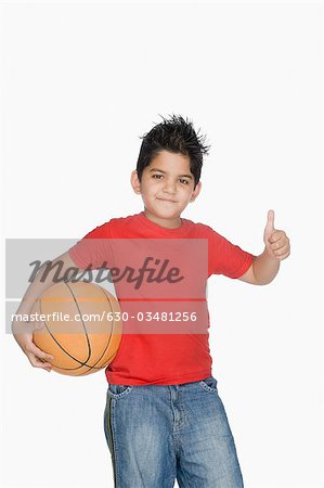 Boy holding a basketball and showing a thumbs up sign