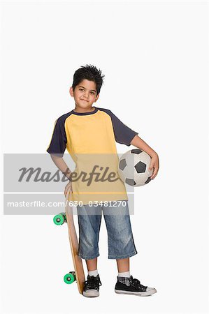 Boy holding a skateboard and a soccer ball