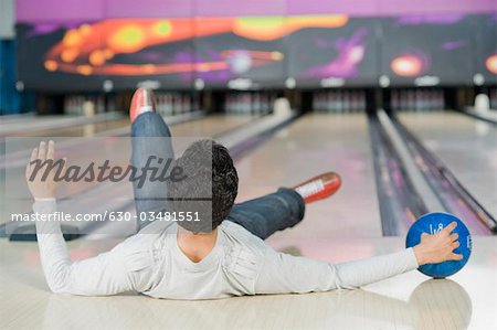 Junger Mann fällt in eine Bowlingbahn