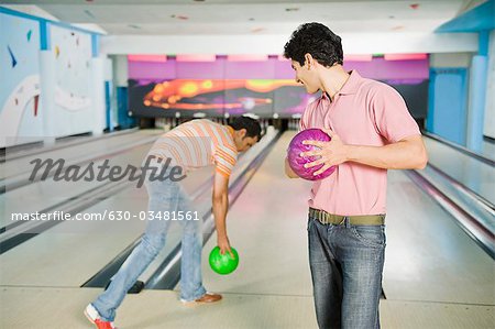 Two young men playing ten pin bowling