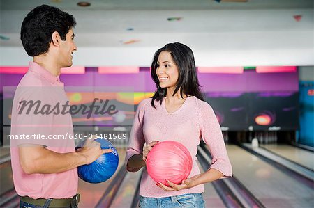 Young couple holding bowling balls in a bowling alley