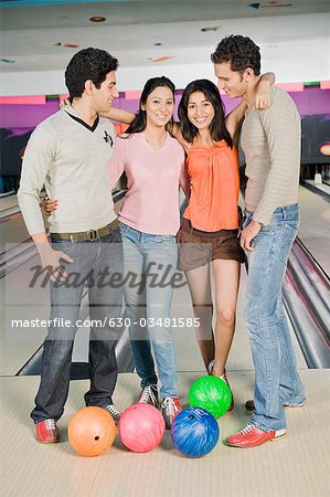 Zwei junge Paare mit Bowlingkugeln in eine Bowlingbahn