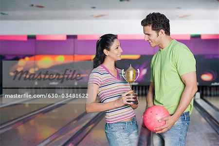 Junges Paar mit einer Bowling-Kugel und eine Trophäe in eine Bowlingbahn