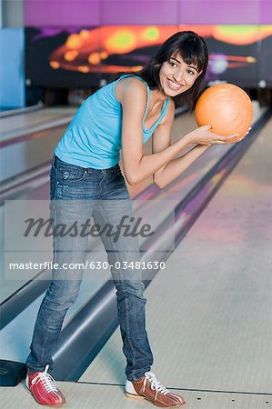 Junge Frau hält eine Bowling-Kugel in eine Bowlingbahn