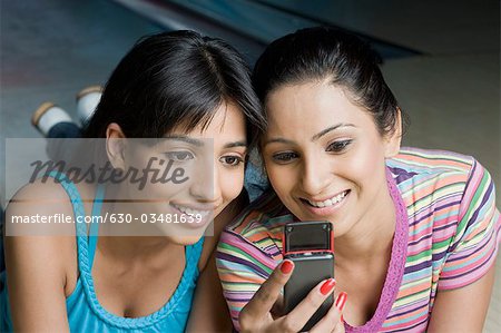 Deux jeunes femmes, en regardant un téléphone mobile dans un bowling